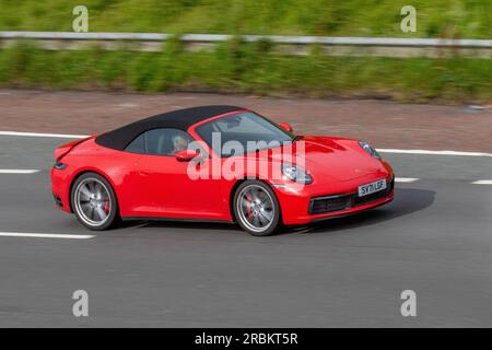 2021 Red Porsche 911 Carrera 4S cabrio, T 450 4S Start/Stop Red benzina Cabriolet Car 2981 cc; viaggia a velocità sostenuta sull'autostrada M6 a Greater Manchester, Regno Unito Foto Stock