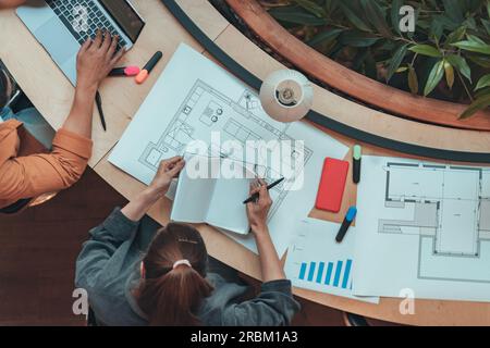 Vista dall'alto di una donna ingegnere architetto che prende appunti durante il lavoro con un progetto di costruzione Foto Stock