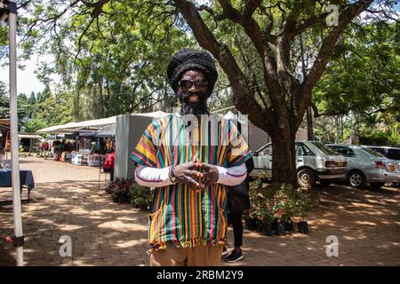 Felice Rastafari che indossa abiti colorati e cappello di lana, con dreadlock e un modo di pensare positivo, anello di pace al dito Foto Stock