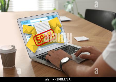 Messaggio di avviso spam, immagini delle buste che fuoriescono dal display del dispositivo. Uomo che usa un software di posta elettronica su un notebook al tavolo, primo piano Foto Stock