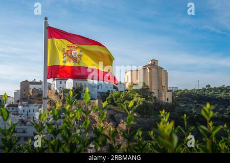 Bandiera di Spagna e Chiesa di la Encarnacion - Setenil de las Bodegas, Andalusia, Spagna Foto Stock