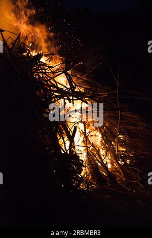 Il lato di un falò brucia con intensità, inviando fiamme e braci nel cielo notturno Foto Stock