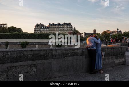 Parigi romantica. Coppia di uomini e donne sulla riva sinistra al tramonto guarda sulla Senna a Pont de l'Archevêché con Ile de la Cité sullo sfondo. Parigi. Foto Stock