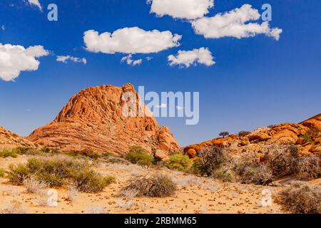 Un monolito del gruppo Spitzkoppe Inselberg nella savana sotto un cielo blu con nuvole di bel tempo, Namibia, Africa Foto Stock