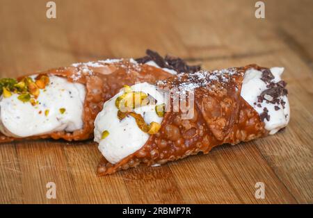 Un cannolo italiano ripieno di crema di ricotta su tavola di legno. Foto Stock