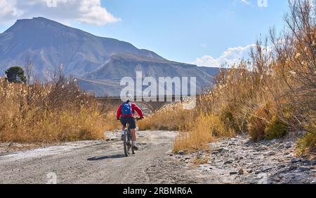 Bella donna anziana attiva con la sua mountain bike elettrica in un tour nel deserto di Tabernas vicino ad Almeria, Andlusia, Spagna Foto Stock