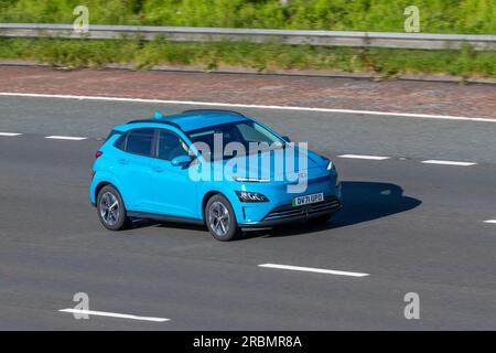 2022 Blue Hyundai Kona Premium EV, 204 PMSM 64 KWH Auto Hatchback elettricità 150 kW viaggiando a velocità sostenuta sull'autostrada M6 a Greater Manchester, Regno Unito Foto Stock