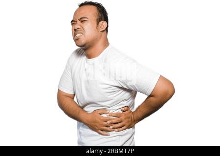Foto di un giovane malato malato malato con la maglietta tenere la mano sullo stomaco soffre di dolore isolato su sfondo bianco Foto Stock