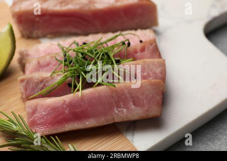 Pezzi di deliziosa bistecca di tonno con microgreen e rosmarino a bordo, primo piano Foto Stock