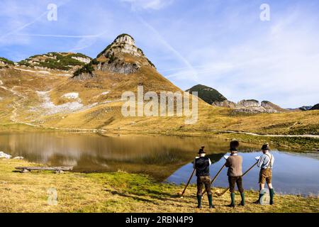 Tre musicisti austriaci di alphorn di nome "Klangholz" suonano l'alphorn al lago Augstsee sul monte Loser in Austria. Foto Stock
