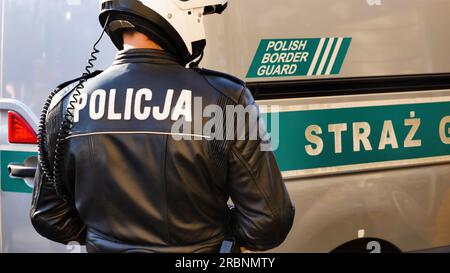 Policja agente di polizia polacco, vicino a un veicolo di guardia di frontiera, dettaglio, poliziotto visto dalla schiena, primo piano, notizie editoriali sparate, pattuglia di frontiera, proteggere Foto Stock