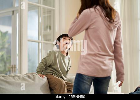 la giovane madre asiatica e il figlio cattivo si stanno confrontando a casa Foto Stock