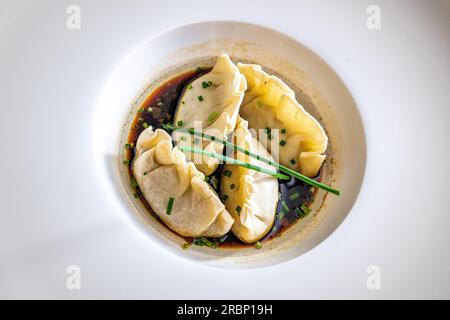 "Un primo piano da una prospettiva dall'alto verso il basso con gnocchi cinesi in un saporito brodo speziato. Foto Stock