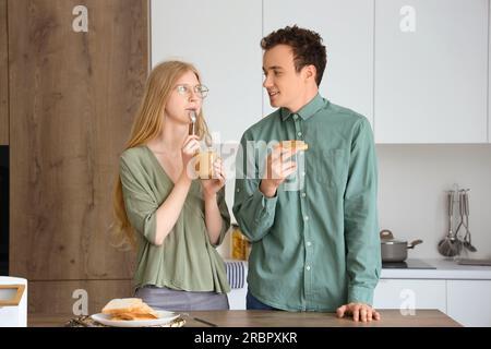 Giovane donna che mangia burro di noci e bell'uomo con pane tostato in cucina Foto Stock