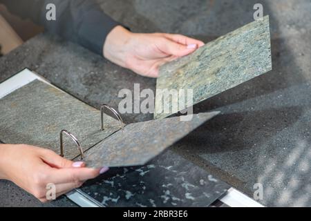 Primi piani di campioni di pietra artificiale nelle mani. Inserti in pietra naturale per la finitura di elementi interni e mobili. Foto Stock