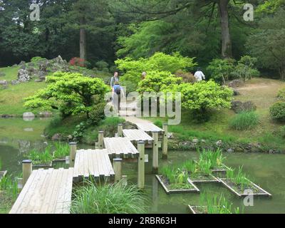 Harmony in Ritsurin Garden, Giappone: Un ponte di legno che attraversa lo stagno ha un design a zig-zag, in quanto il male non può attraversare l'altro lato in linee rette. Foto Stock