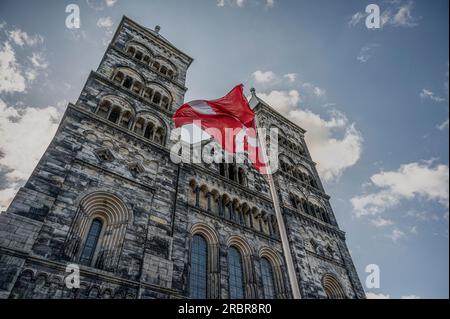 Le torri gemelle della cattedrale di Lund con la bandiera danese rossa e bianca contro il cielo estivo, Lund, Svezia, 2 luglio 2023 Foto Stock