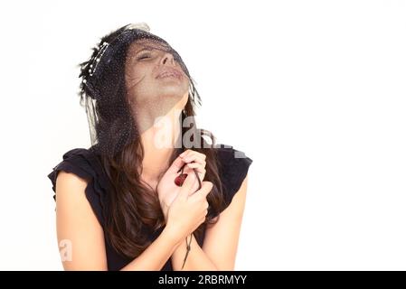 Sconvolta teary giovane donna con le mani giunte in angoscia in piedi con gli occhi upcastcast contro un bianco di sfondo per studio Foto Stock