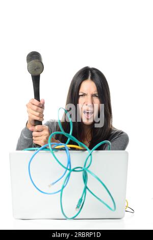 Donna arrabbiata che schiaccia il suo notebook con cavi di rete aggrovigliati utilizzando Large Hammer. Isolato su sfondo bianco Foto Stock