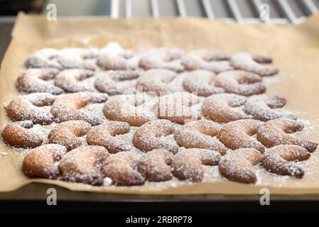 Sullo sfondo di un tradizionale a forma di mezzaluna biscotti di Natale o biscotti con nitide golden sfoglia cosparsa di zucchero su un banco di cucina Foto Stock