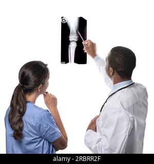 Vista da dietro di un competente team medico multietnico composto da medico e chirurgo ortopedico consultando una radiografia di un'articolazione che punta ad esso Foto Stock