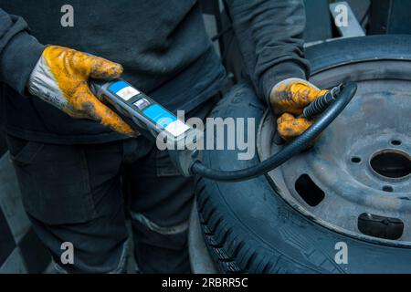 L'addetto all'assistenza misura la pressione dell'aria del nuovo pneumatico Foto Stock