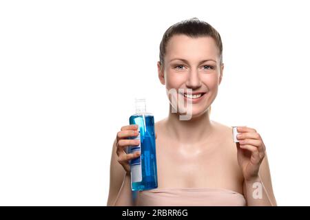 Primo piano Smiling Young Woman che tiene una bottiglia di collutorio in un berretto mentre guarda la fotocamera, isolata su sfondo bianco Foto Stock