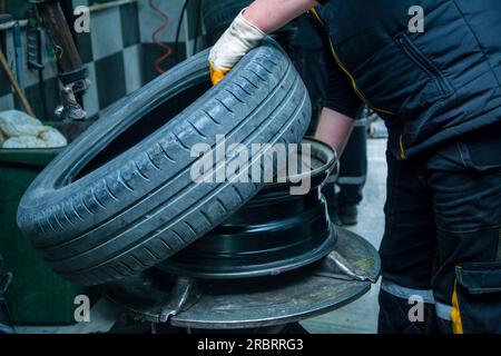 Vista dell'operatore addetto alla manutenzione con lo pneumatico rimosso dal cerchio Foto Stock