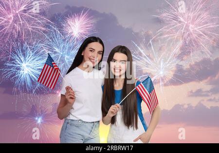 4 luglio - giorno dell'indipendenza dell'America. Madre e figlia felici che reggono bandiere nazionali degli Stati Uniti contro il cielo con fuochi d'artificio Foto Stock