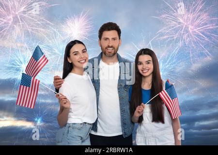 4 luglio - giorno dell'indipendenza dell'America. Famiglia felice che tiene bandiere nazionali degli Stati Uniti contro il cielo con fuochi d'artificio Foto Stock