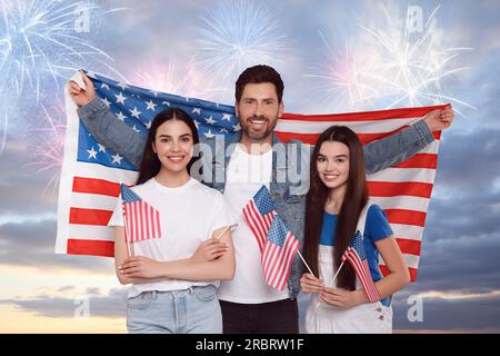 4 luglio - giorno dell'indipendenza dell'America. Famiglia felice che tiene bandiere nazionali degli Stati Uniti contro il cielo con fuochi d'artificio Foto Stock