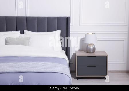 Comodo letto vicino a un comodino con lampada in una camera da letto  elegante Foto stock - Alamy