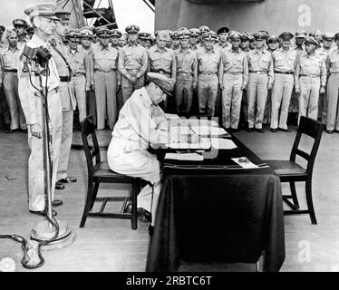 Tokyo, Giappone: 1 settembre 1945 il generale dell'esercito Douglas MacArthur firma come comandante supremo alleato durante la cerimonia formale di resa giapponese a bordo della USS Missouri nella baia di Tokyo. Foto Stock