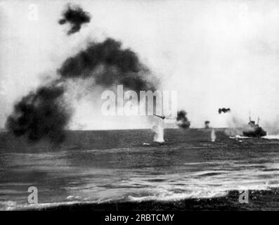 Midway Island, Oceano Pacifico: Giugno 1942 fumo e beccucci d'acqua derivanti dalla caduta di bombe oscurano un U.S. Nave della Marina a destra durante un attacco aereo giapponese durante la battaglia di Midway Island. Foto Stock
