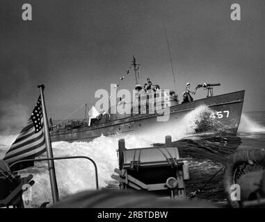 Oceano Pacifico meridionale, circa 1943 Un sottomarino della Guardia Costiera degli Stati Uniti in pattuglia di convogli mentre passa da un'altra motovedetta della Guardia Costiera carica di cariche di profondità sulla sua poppa. Foto Stock