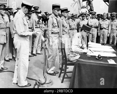 Tokyo, Giappone: 1 settembre 1945 con altri delegati francesi in piedi dietro di lui, il generale francese Jacques le Clerc firma per la Francia durante la cerimonia di resa giapponese a bordo della USS Missouri nella baia di Tokyo. STATI UNITI Il generale dell'esercito Douglas MacArthur si trova a sinistra vicino al microfono. Foto Stock