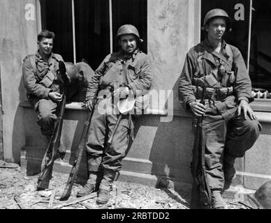 Villedieu, Francia, 4 agosto 1944 Pvt Charles E. Frady, Rocky Mount, North Carolina, Asst Sqd LDR Raymond E. Taber, St. Louis, Missouri e PFC John R. Garstrom, Jamestown, New York, fanno una breve pausa durante un viaggio di fanteria Yank nel villaggio di Villedieu. Foto Stock