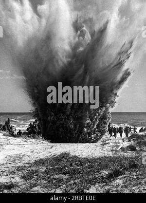 Stati Uniti, 13 maggio 1943 US Coast Guardsmen tattiche di invasione del parcticing mentre un'esplosione di mine di terra aggiunge realtà alla manovra. Foto Stock