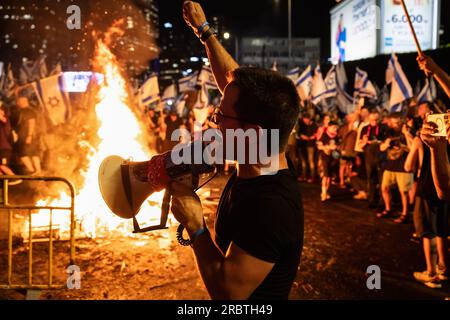 Tel Aviv, Israele. 5 luglio 2023. I manifestanti contro la riforma cantano intorno a un falò sull'autostrada Aayalon bloccata durante la manifestazione. Migliaia di israeliani sono scesi in strada e hanno bloccato l'autostrada Ayalon a Tel Aviv scontrandosi con la polizia che ha usato cannoni ad acqua e ufficiali di polizia a cavallo e arresti per disperdere i manifestanti dopo che il capo della polizia di Tel Aviv Amichai Eshed ha annunciato le sue dimissioni dalla forza. (Immagine di credito: © Matan Golan/SOPA Images via ZUMA Press Wire) SOLO USO EDITORIALE! Non per USO commerciale! Foto Stock