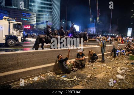 Tel Aviv, Israele. 5 luglio 2023. I manifestanti anti anti-riforma si nascondono dagli ufficiali di polizia a cavallo e dai cannoni ad acqua durante la manifestazione. Migliaia di israeliani sono scesi in strada e hanno bloccato l'autostrada Ayalon a Tel Aviv scontrandosi con la polizia che ha usato cannoni ad acqua e ufficiali di polizia a cavallo e arresti per disperdere i manifestanti dopo che il capo della polizia di Tel Aviv Amichai Eshed ha annunciato le sue dimissioni dalla forza. (Immagine di credito: © Matan Golan/SOPA Images via ZUMA Press Wire) SOLO USO EDITORIALE! Non per USO commerciale! Foto Stock