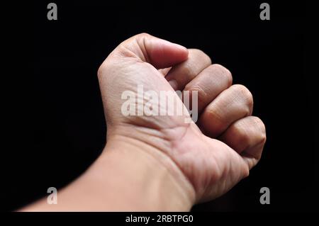 Foto a fuoco selettiva della mano sinistra bloccata su sfondo nero Foto Stock