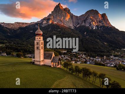 Seis am Schlern, Italia - St. Valentin e il famoso monte Sciliar con nuvole colorate, cielo blu e luce solare calda in alto Adige Foto Stock