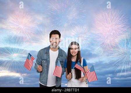 4 luglio - giorno dell'indipendenza dell'America. Buon padre e sua figlia che reggono bandiere nazionali degli Stati Uniti contro il cielo con fuochi d'artificio Foto Stock