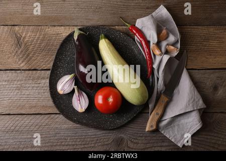 Cucinare ratatouille. Verdure e coltello su tavola di legno, posate in piano Foto Stock