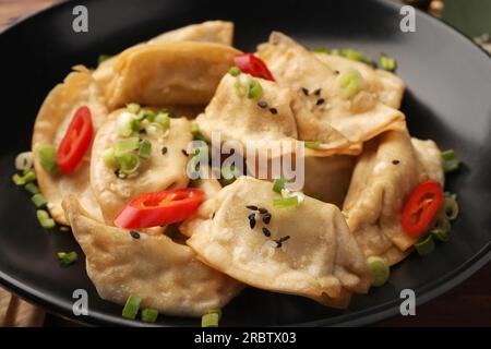 Delizioso gyoza (gnocchi asiatici) con semi di sesamo, cipolle verdi e peperoncino in ciotola, primo piano Foto Stock