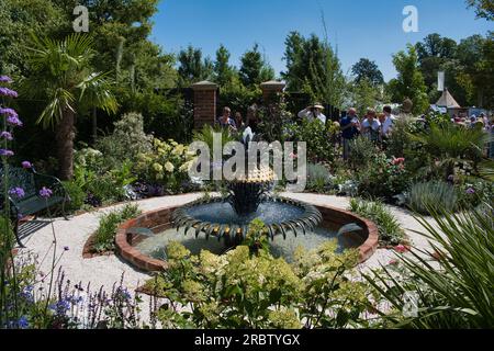 I visitatori ammirano uno dei giardini dello spettacolo al RHS Hampton Court Flower Show di Londra Foto Stock