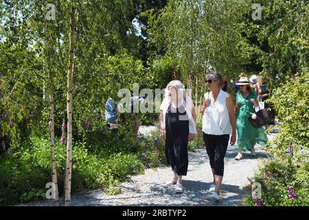 I visitatori ammirano uno dei giardini dello spettacolo al RHS Hampton Court Flower Show di Londra Foto Stock