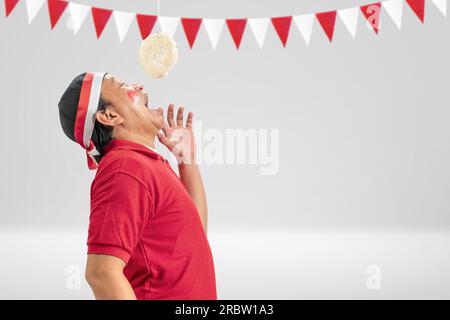 Gli uomini indonesiani celebrano il giorno dell'indipendenza indonesiana il 17 agosto con la competizione dei cracker che mangiano. Giorno dell'indipendenza indonesiana Foto Stock