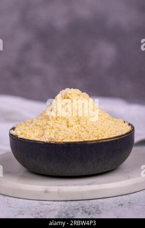Farina di mais su fondo di pietra. Farina di mais nel recipiente. primo piano Foto Stock