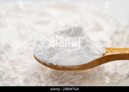 Amido di grano su cucchiaio di legno. spezie o condimenti come sfondo. Amido di frumento da vicino Foto Stock